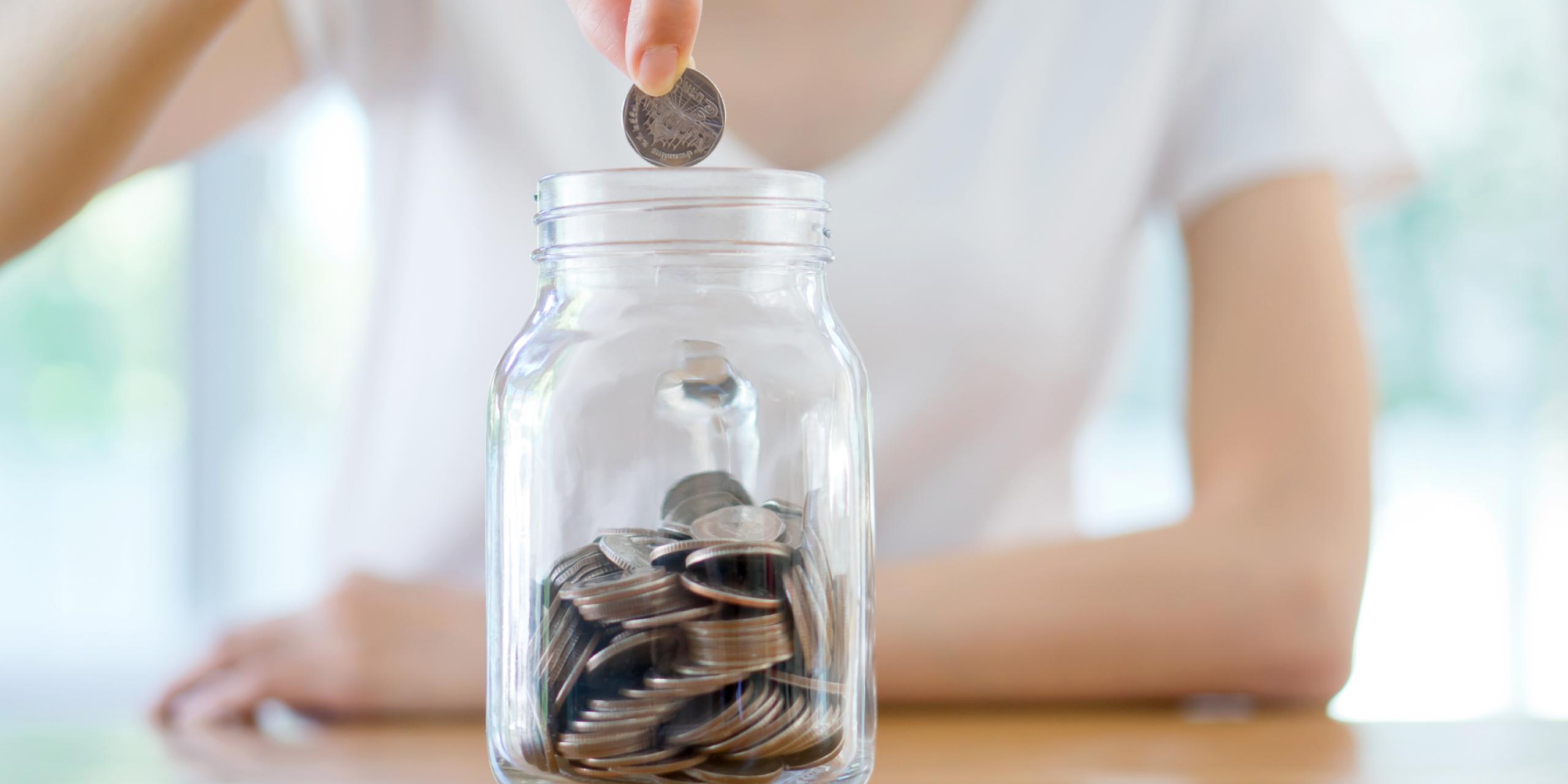 Photo of a woman placing money in a jar. 
