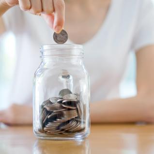 Photo of a woman placing money in a jar. 